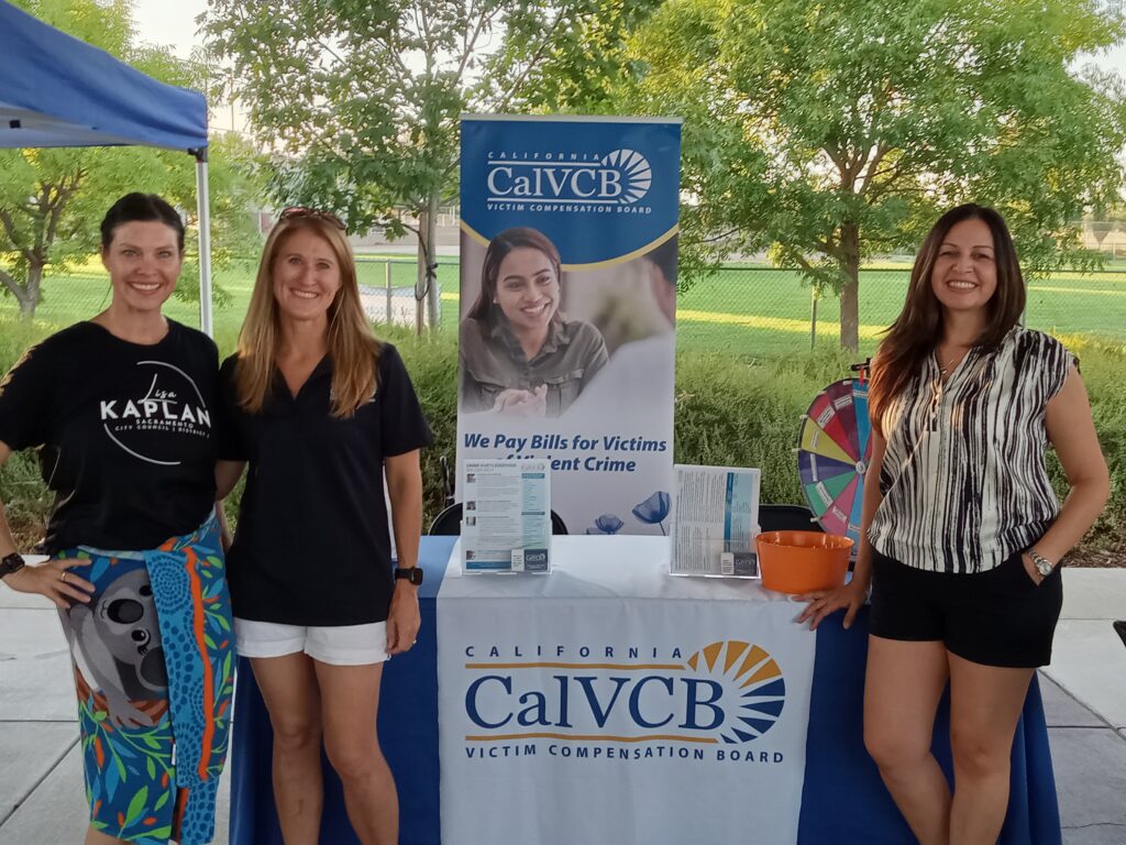 Three women in front of an informational booth.